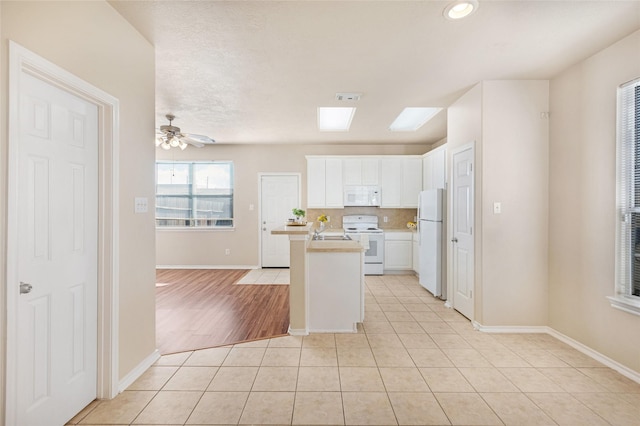 kitchen featuring white cabinetry, backsplash, light tile patterned floors, ceiling fan, and white appliances