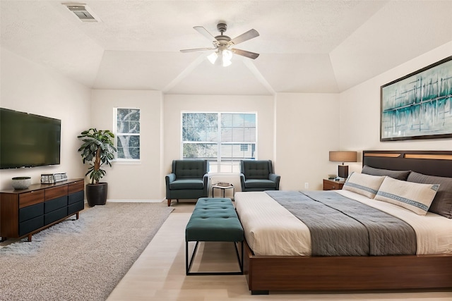 bedroom featuring vaulted ceiling, light colored carpet, a raised ceiling, and ceiling fan