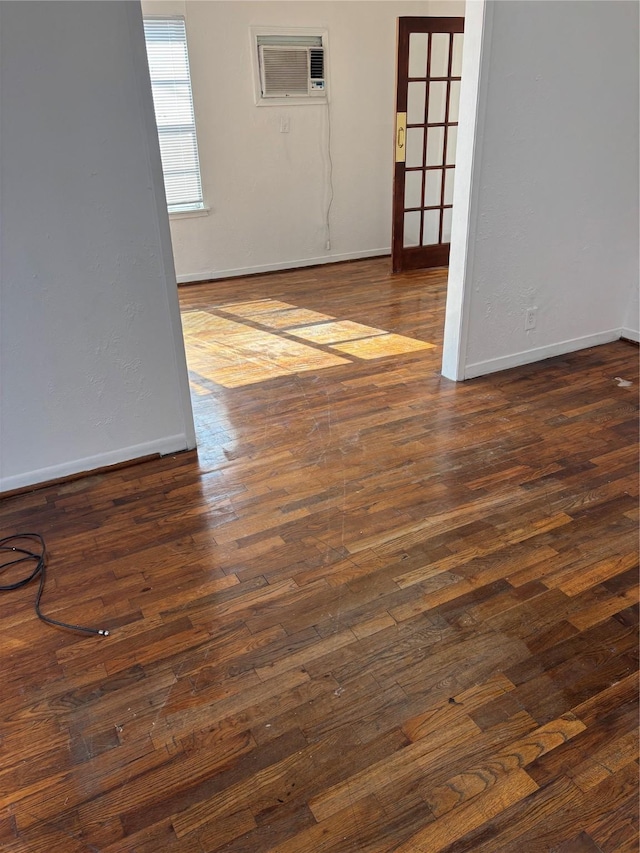 empty room with a wall unit AC and dark hardwood / wood-style floors