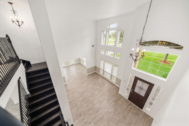 foyer entrance with a high ceiling, stairs, a chandelier, and wood finished floors