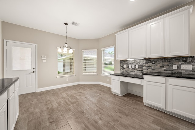 kitchen with tasteful backsplash, visible vents, white cabinets, built in study area, and light wood-type flooring