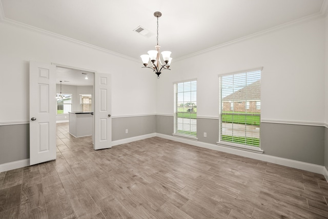 empty room with hardwood / wood-style floors, a notable chandelier, and crown molding