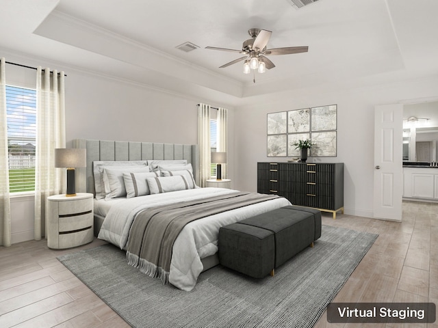 bedroom with light wood-type flooring, a raised ceiling, visible vents, and crown molding