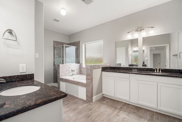 bathroom with a garden tub, two vanities, visible vents, a stall shower, and a sink