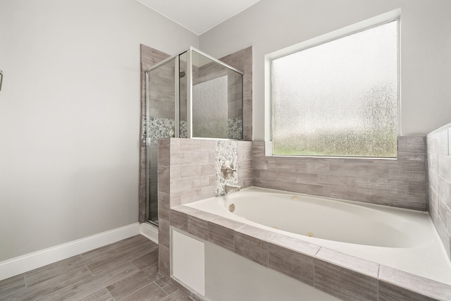 full bathroom featuring a garden tub, a shower stall, and baseboards