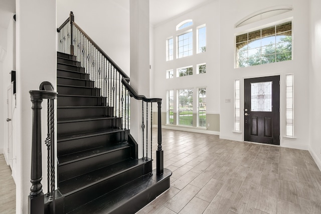 entryway featuring a high ceiling, stairway, wood finished floors, and baseboards