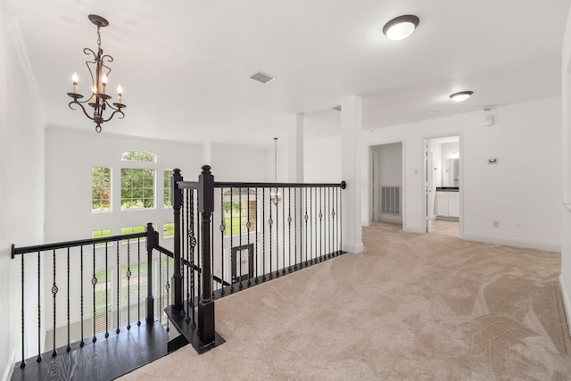 corridor featuring baseboards, visible vents, a chandelier, and light colored carpet