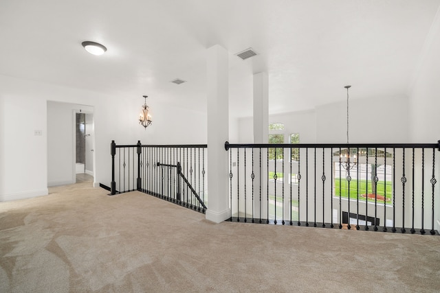 hallway with light colored carpet and a chandelier