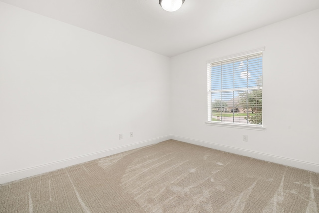 unfurnished room featuring light carpet and baseboards