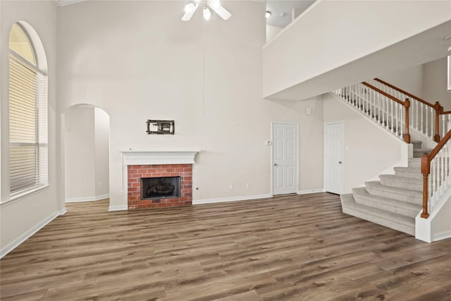 unfurnished living room with dark hardwood / wood-style floors, a high ceiling, and a brick fireplace