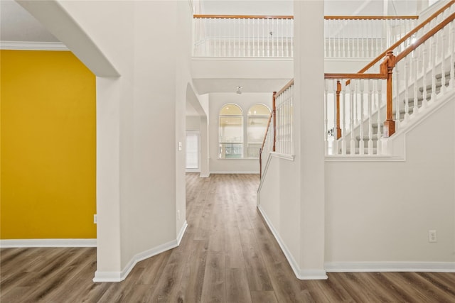 hall featuring hardwood / wood-style floors, ornamental molding, and a high ceiling