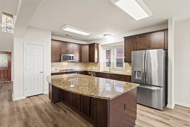 kitchen featuring a center island, sink, light stone countertops, and stainless steel appliances