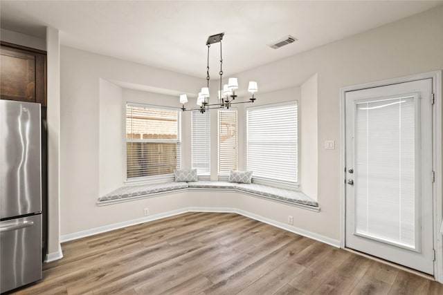 unfurnished dining area with wood-type flooring and an inviting chandelier