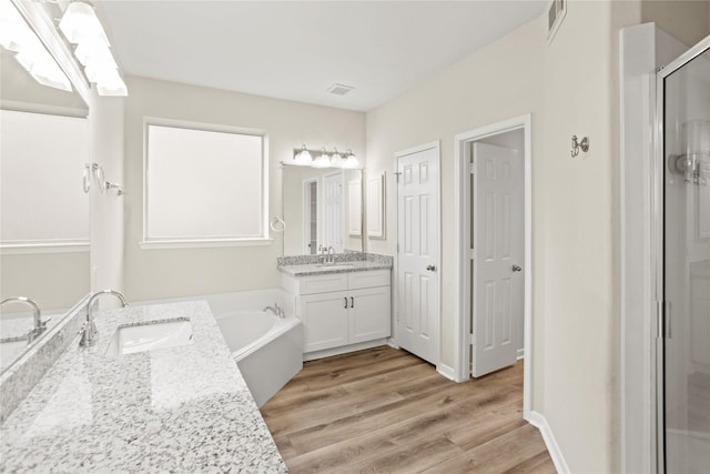 bathroom featuring hardwood / wood-style floors, vanity, and plus walk in shower