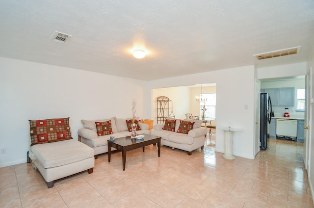 tiled living room with a textured ceiling and a notable chandelier