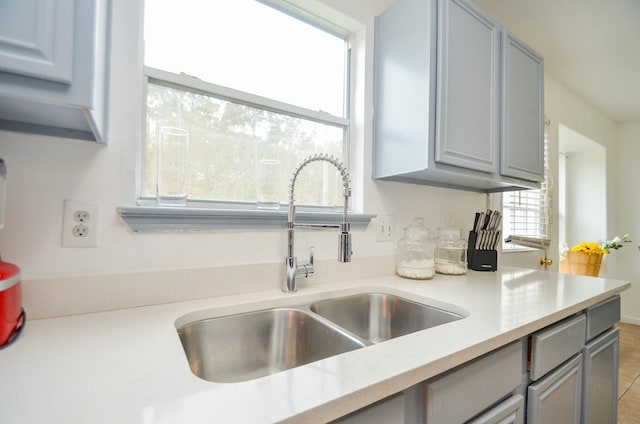 kitchen with gray cabinetry, sink, and a wealth of natural light