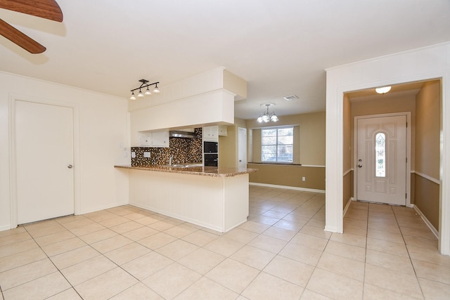 kitchen featuring light tile patterned flooring, a peninsula, visible vents, tasteful backsplash, and decorative light fixtures