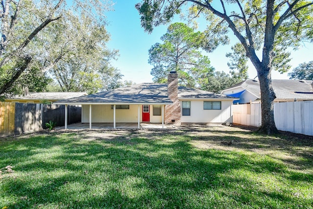 back of property featuring a fenced backyard, a chimney, a lawn, and a patio