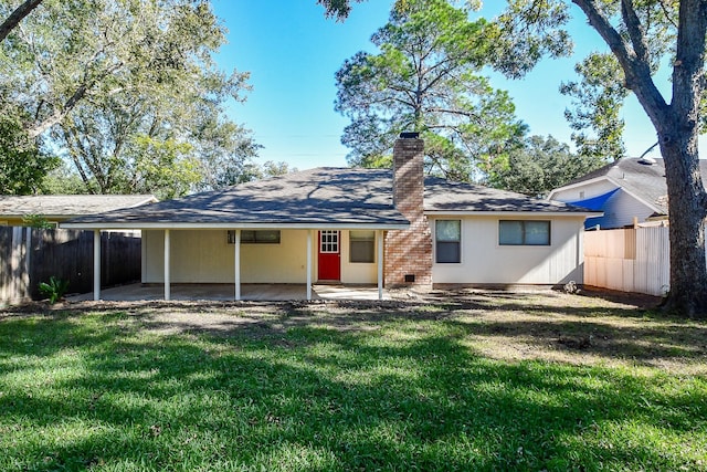 back of property featuring fence, a yard, a carport, a chimney, and a patio area