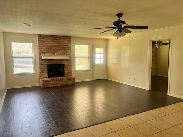 unfurnished living room with a textured ceiling, a fireplace, wood finished floors, and visible vents