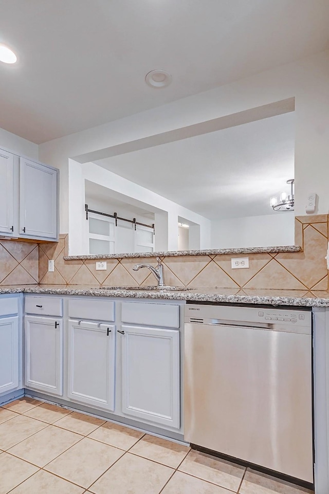 kitchen featuring dishwasher, light stone countertops, light tile patterned floors, tasteful backsplash, and white cabinetry