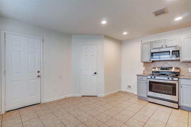 kitchen featuring light stone countertops, appliances with stainless steel finishes, tasteful backsplash, and light tile patterned floors