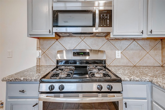 kitchen featuring white cabinetry, decorative backsplash, light stone counters, and appliances with stainless steel finishes