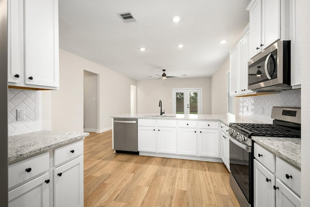 kitchen with ceiling fan, kitchen peninsula, decorative backsplash, white cabinets, and appliances with stainless steel finishes