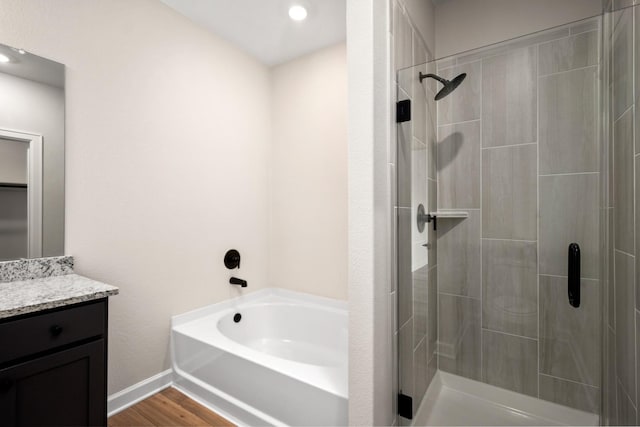 bathroom featuring plus walk in shower, wood-type flooring, and vanity