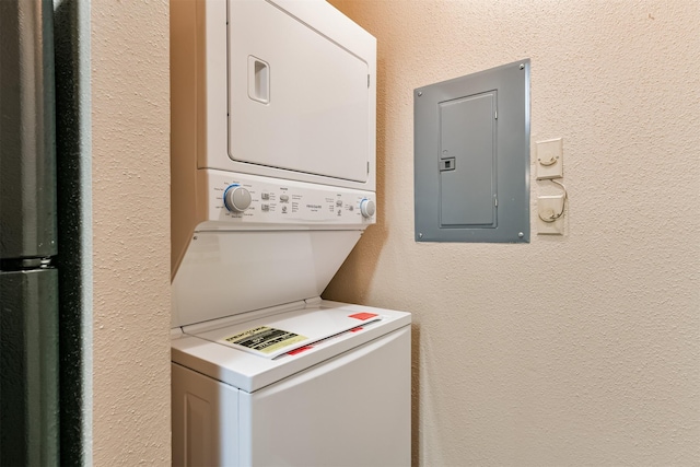 laundry area with electric panel and stacked washer / drying machine