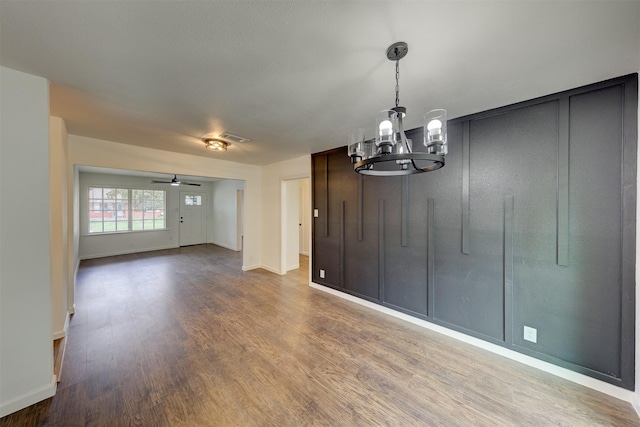 empty room featuring hardwood / wood-style floors and ceiling fan with notable chandelier