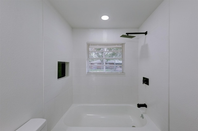 bathroom with tiled shower / bath combo and toilet