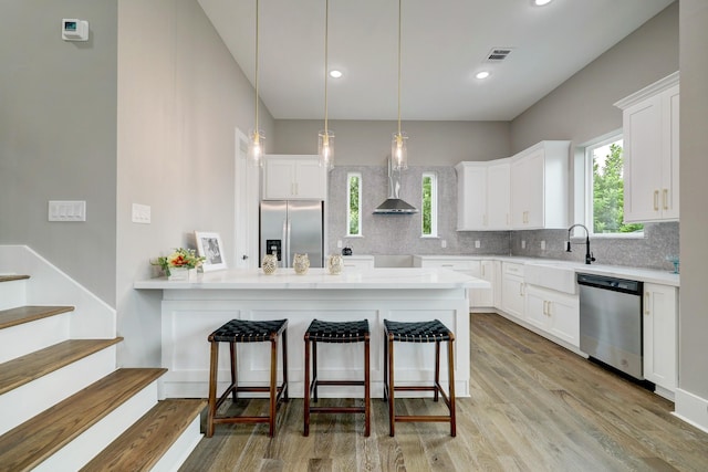 kitchen with white cabinetry, sink, decorative light fixtures, and stainless steel appliances