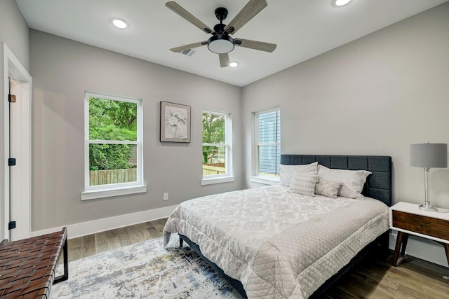 bedroom featuring hardwood / wood-style flooring, ceiling fan, and multiple windows