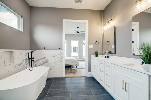 bathroom with ceiling fan, vanity, tile walls, and a washtub