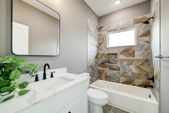 full bathroom featuring vanity, tiled shower / bath combo, and toilet