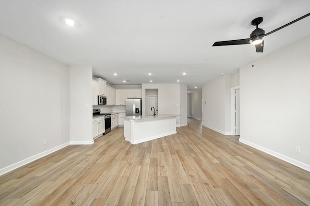 kitchen featuring a center island with sink, sink, light wood-type flooring, white cabinetry, and stainless steel appliances