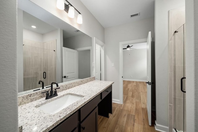 bathroom with wood-type flooring, vanity, ceiling fan, and a shower with shower door