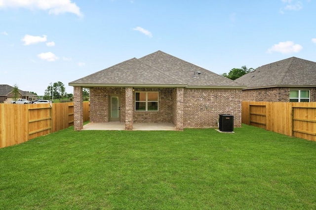 rear view of property featuring a yard, cooling unit, and a patio area