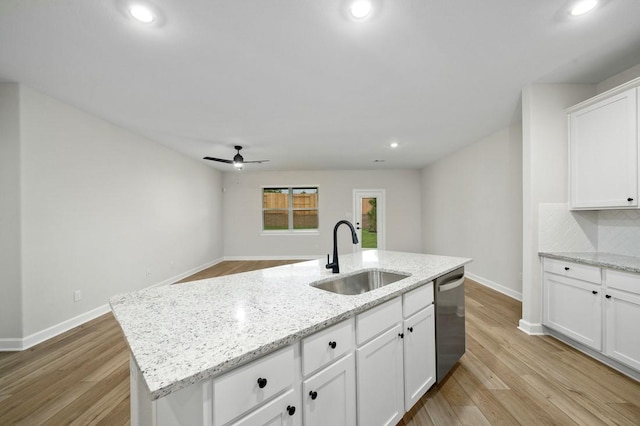 kitchen featuring decorative backsplash, stainless steel dishwasher, a kitchen island with sink, sink, and white cabinets