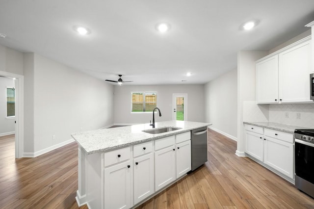 kitchen featuring sink, an island with sink, decorative backsplash, white cabinets, and appliances with stainless steel finishes