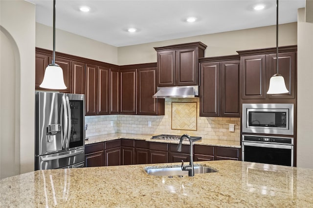 kitchen with decorative backsplash, appliances with stainless steel finishes, light stone counters, sink, and pendant lighting