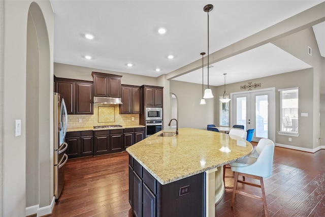 kitchen with french doors, a kitchen breakfast bar, decorative backsplash, a large island, and stainless steel appliances