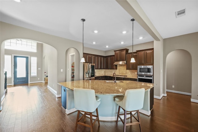 kitchen with a large island, light stone countertops, hanging light fixtures, and appliances with stainless steel finishes