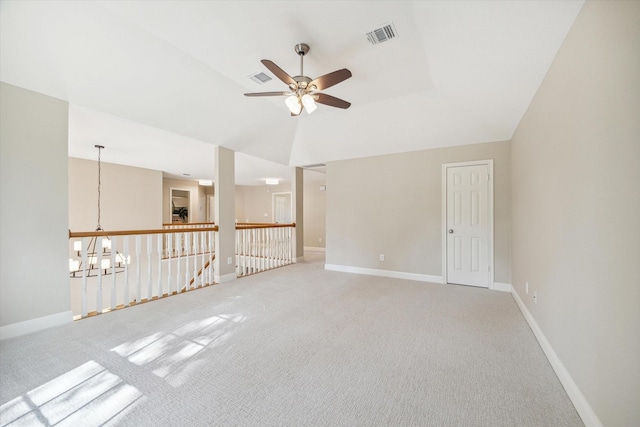 empty room featuring vaulted ceiling, carpet, and ceiling fan with notable chandelier