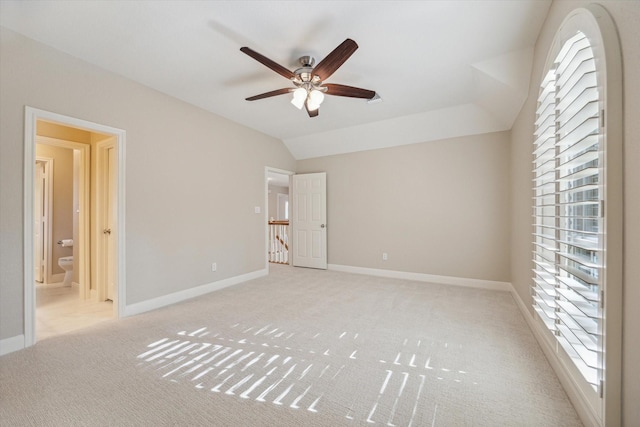 unfurnished bedroom with ensuite bath, light colored carpet, ceiling fan, and multiple windows