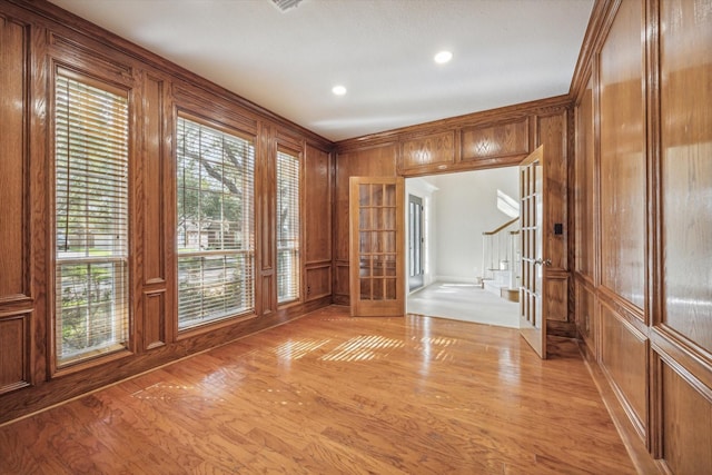 entryway featuring light hardwood / wood-style flooring, french doors, wooden walls, and crown molding