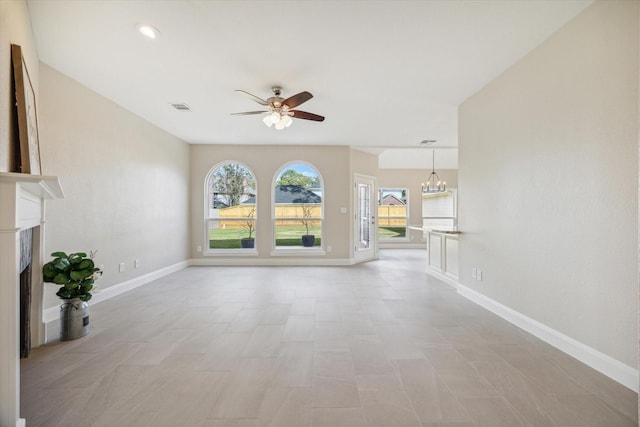 unfurnished living room featuring ceiling fan with notable chandelier