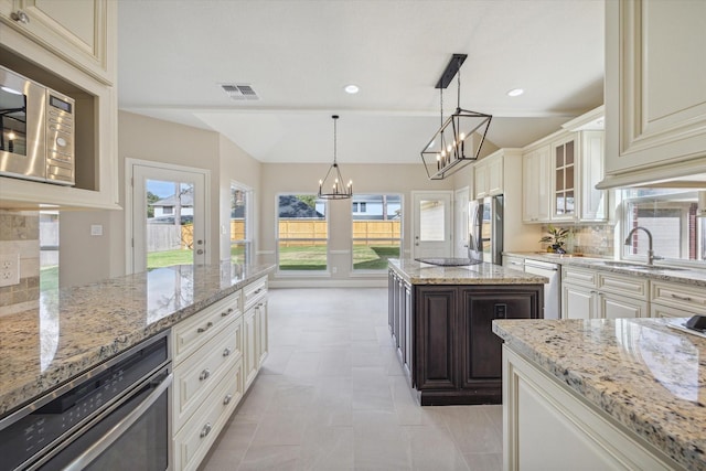 kitchen featuring stainless steel appliances, a chandelier, backsplash, and light stone countertops