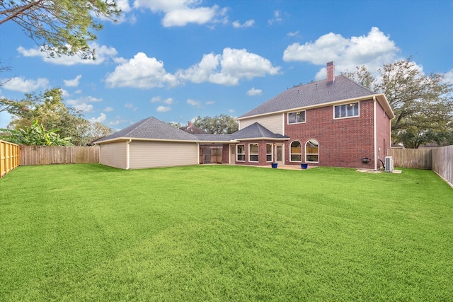 rear view of property featuring a lawn and central air condition unit